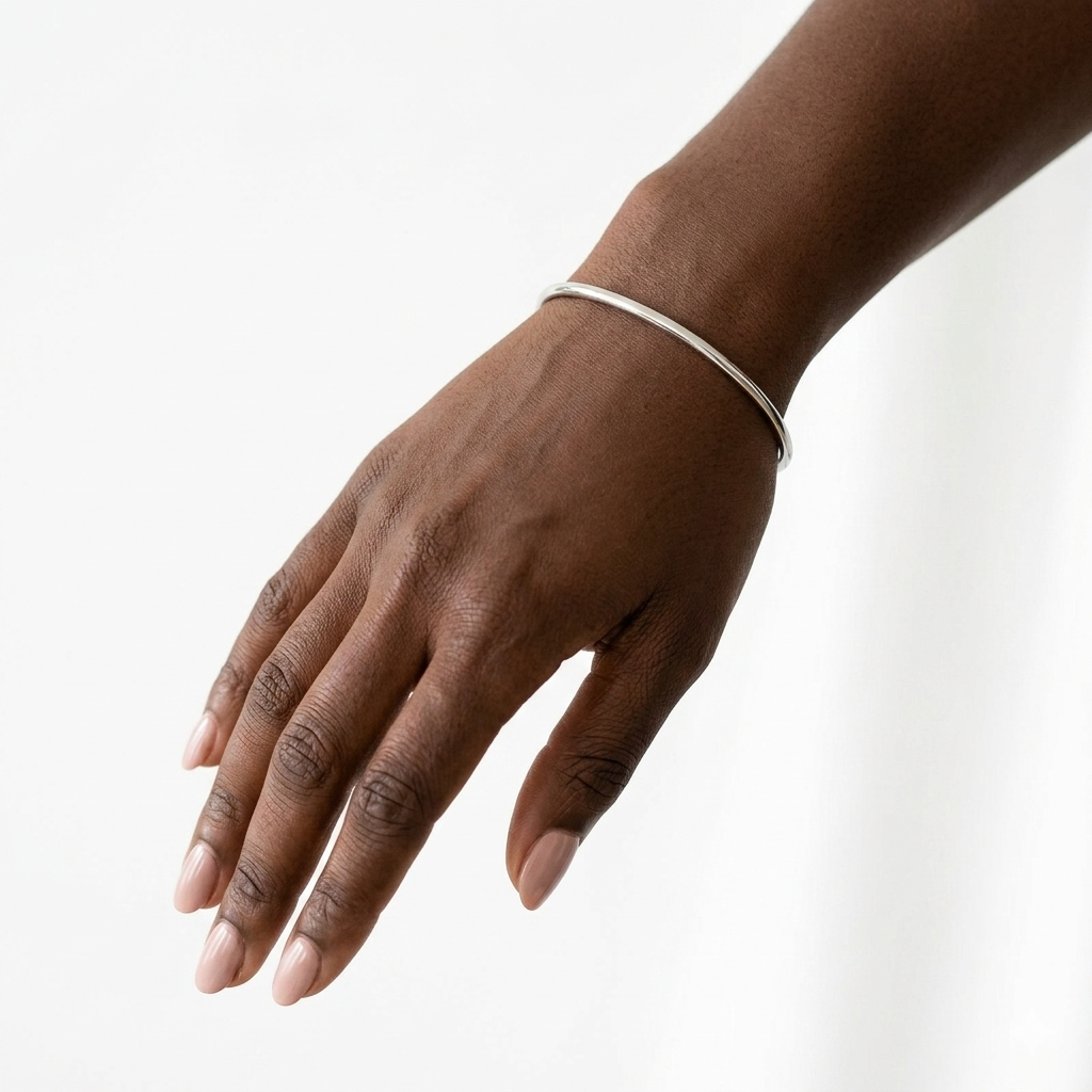 Jonc Elle argenté porté au poignet peau foncée fond blanc minimaliste KD Softy Bijoux