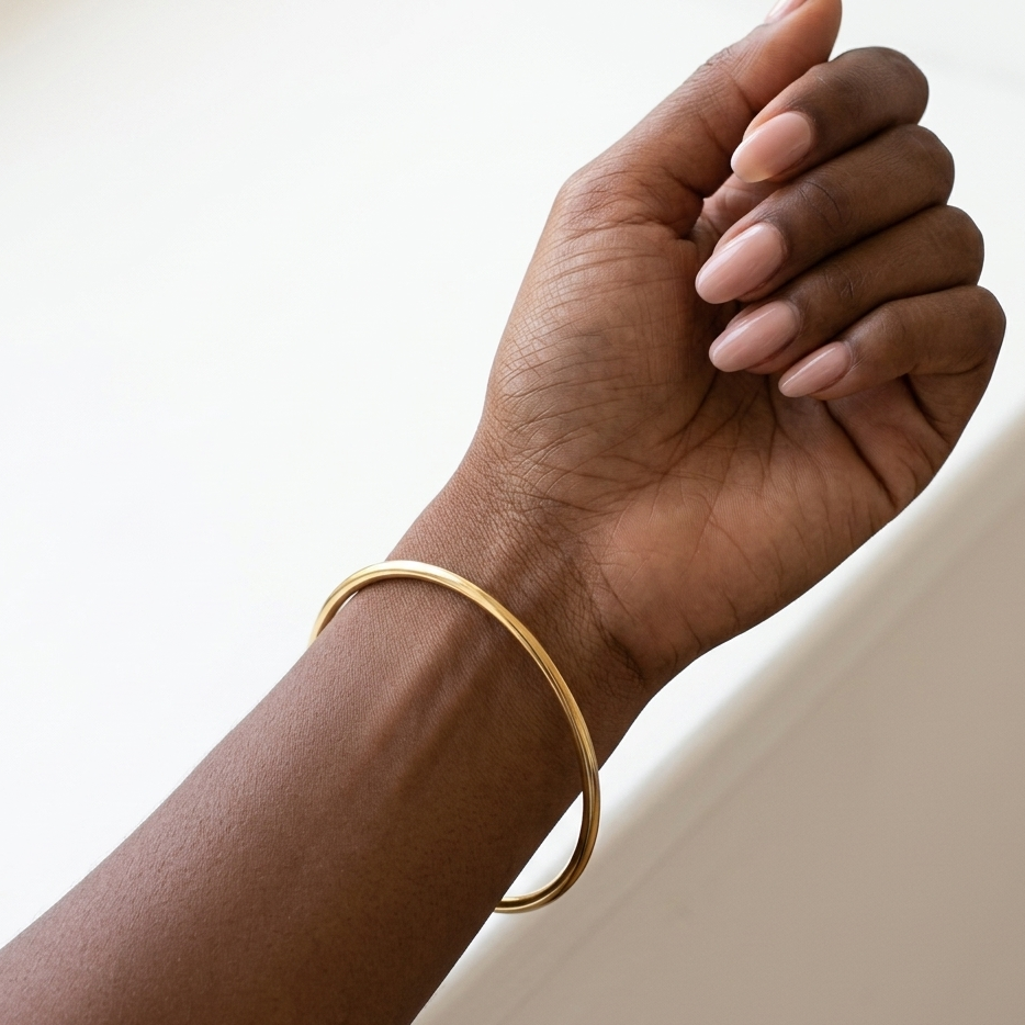 Jonc Elle doré porté au poignet peau noire fond blanc minimaliste KD Softy Bijoux